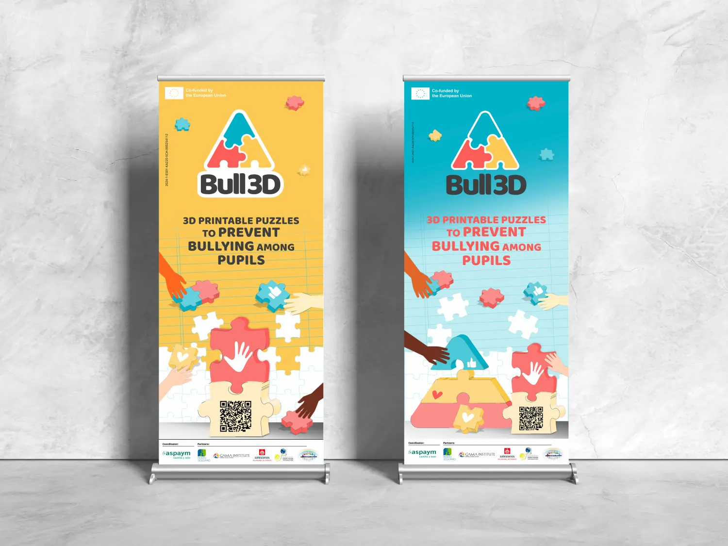 Dois roll-up´s do projeto Bull3D, um com fundo amarelo e o outro com fundo azuk«l, logotipo colorido em forma de puzzle e mensagem '3D printable puzzles to prevent bullying among pupils', rodeado por mãos de diferentes cores montando peças de puzzle.